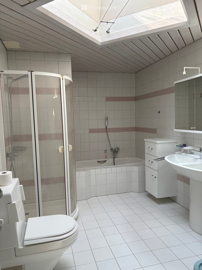 Modern bathroom with white tiles, a bathtub, shower, toilet, sink, and a mirrored cabinet.