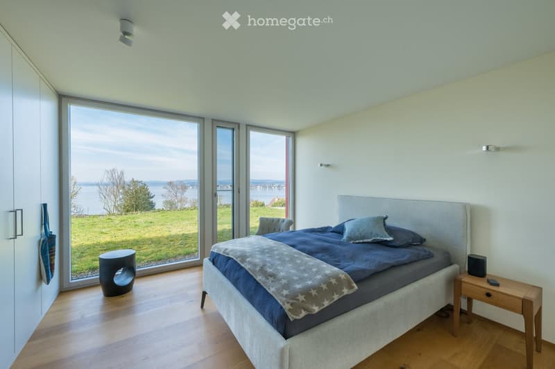 bedroom with large windows, wooden floor, bed, nightstand, view of the lake