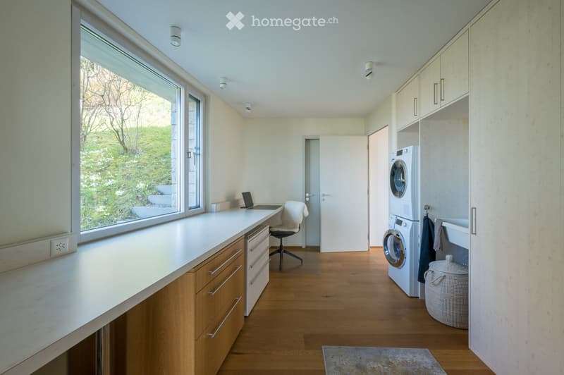 modern laundry room with washing machine, dryer, desk, chair, cabinets, and a window