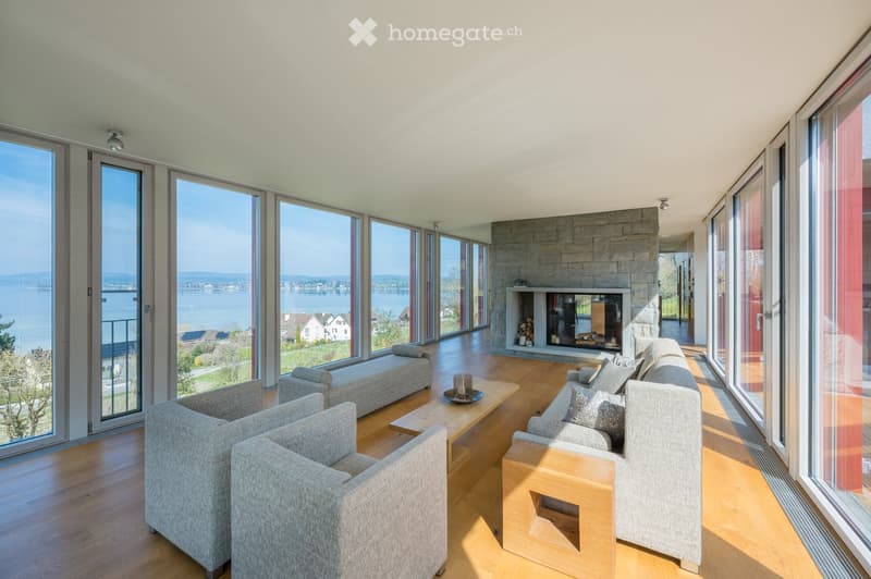 large living room, fireplace, large windows, wooden floor, couches, coffee table, view of the lake