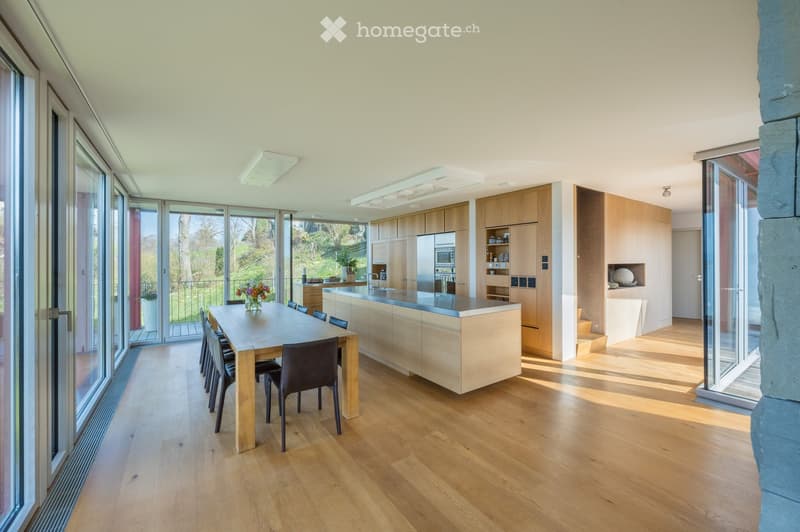 modern kitchen with island, dining table, hardwood floors, large windows, balcony, view of garden