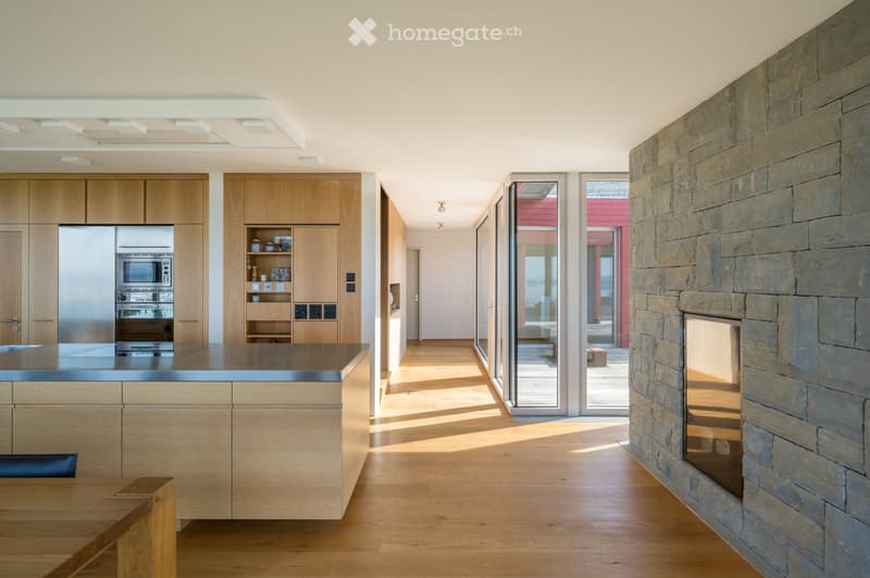 modern kitchen with wooden cabinets, stainless steel appliances, large island, fireplace, sliding glass doors