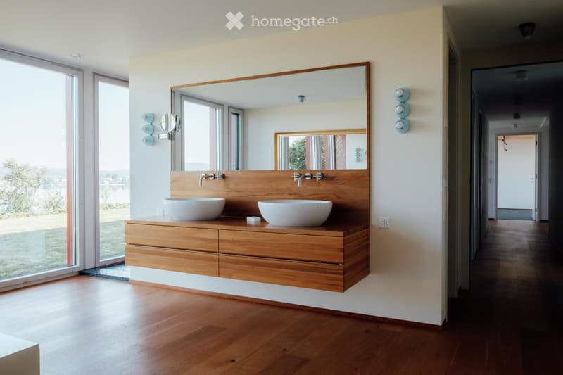 Bathroom with wooden vanity, two sinks, large mirror, wooden floor, large windows