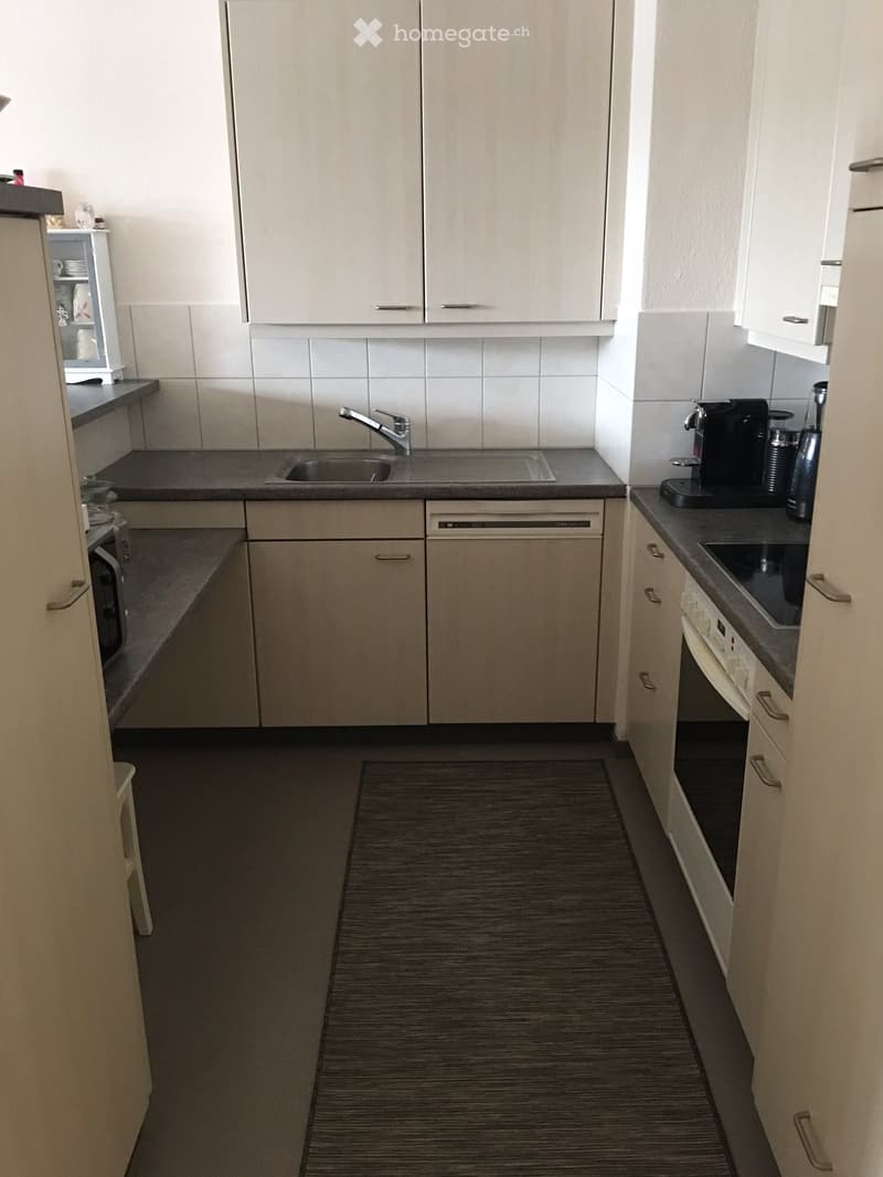 modern kitchen, white cabinets, gray granite countertops, integrated dishwasher, oven, microwave, sink with faucet, and granite flooring.