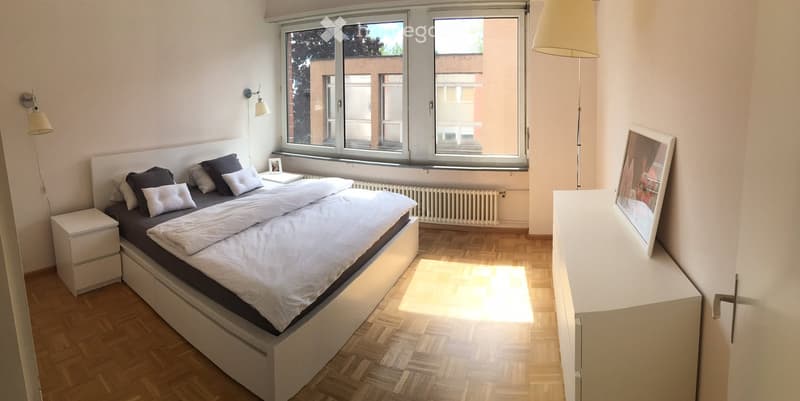 bedroom with bed, white night stands, picture, lamp, radiator, parquet floor