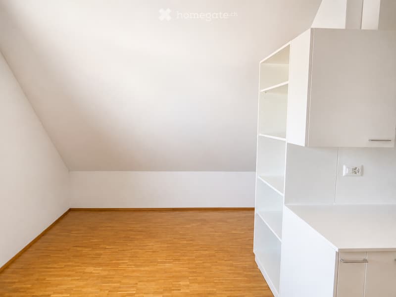 Empty room with white walls, wooden floor, and built-in white shelving unit.