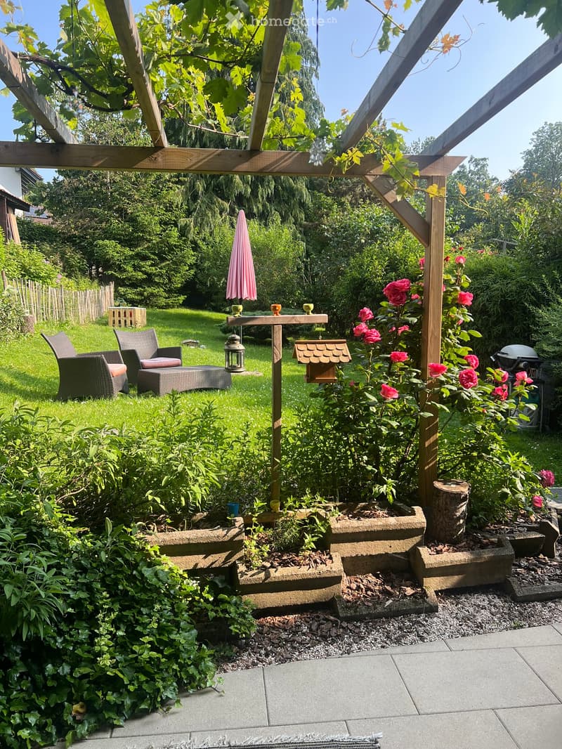Garden / Outdoor Area. Garden with wooden pergola, seating area, rose bushes, and a small table with chairs.