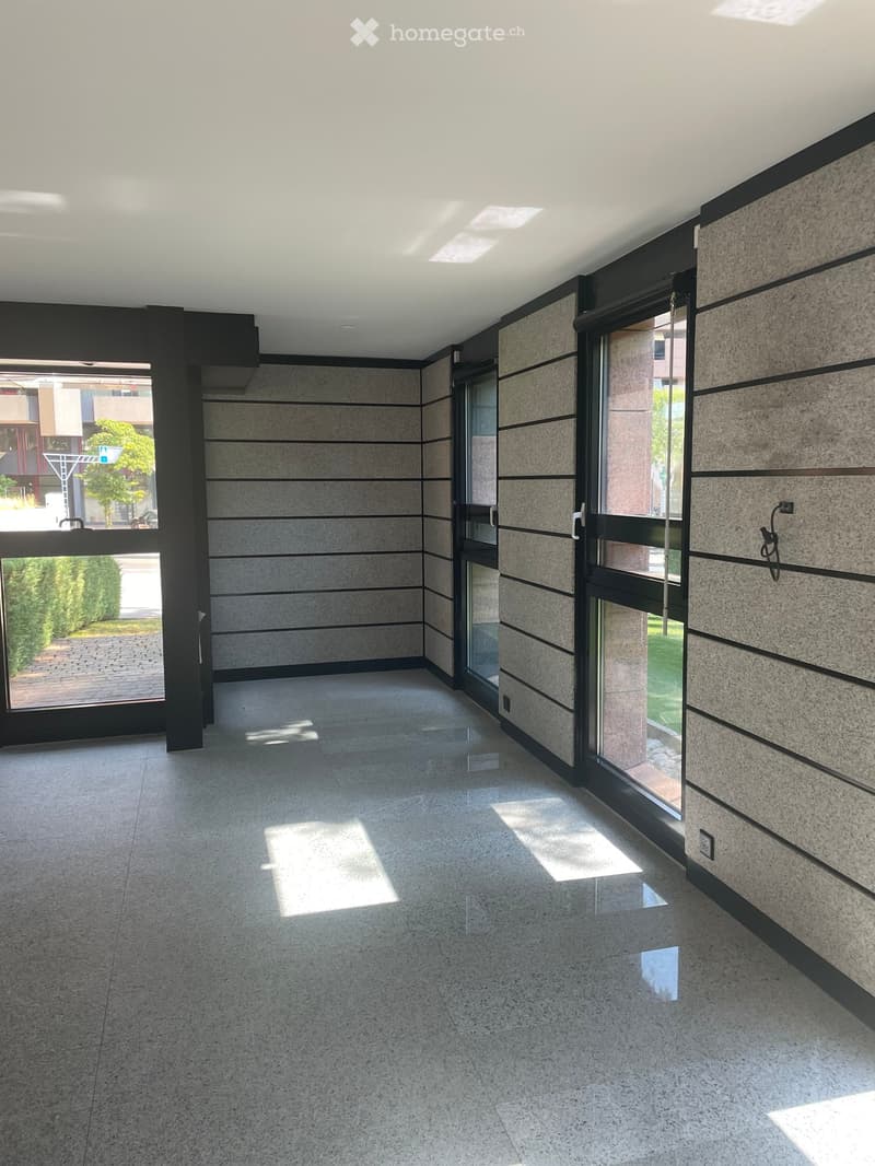 Modern hallway with polished concrete floors, large windows, and sleek, contemporary design featuring vertical stone panels and black accents.