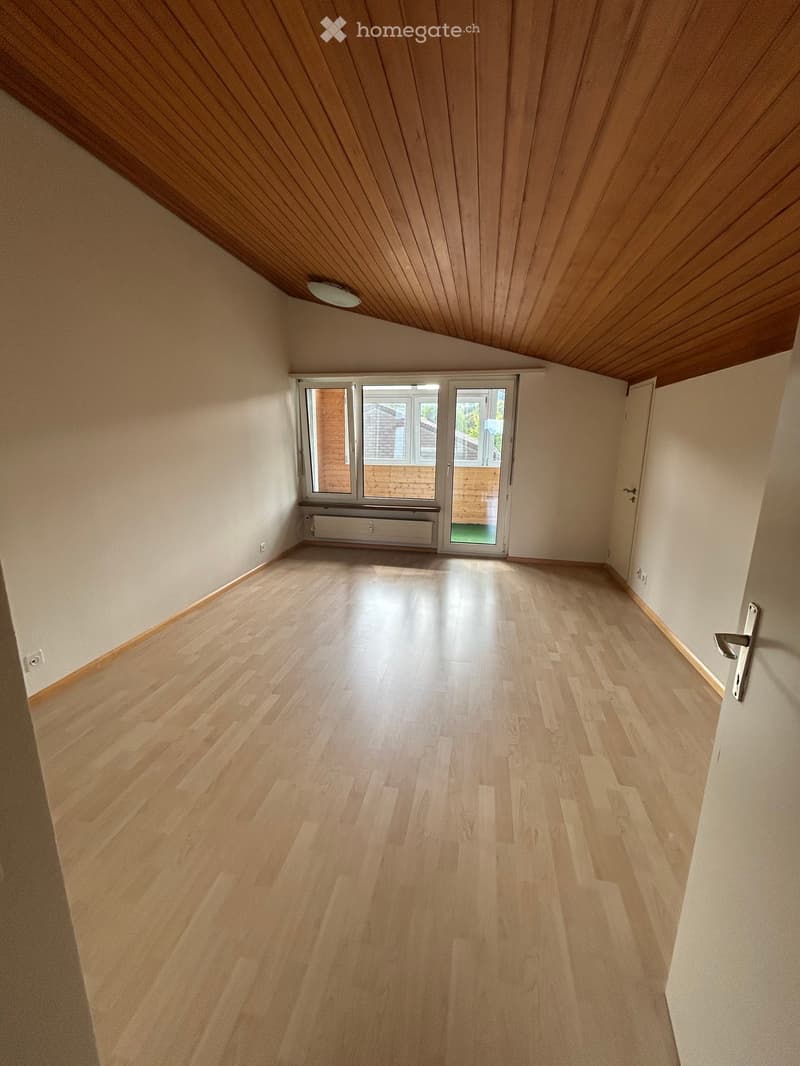 Empty room with light wooden flooring, white walls, and a large window with a sliding door leading to an outdoor area.