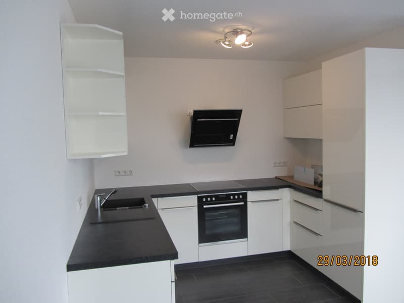 Modern kitchen with white cabinets, black countertops, stainless steel sink and faucet, built-in oven, microwave, and overhead lighting.
