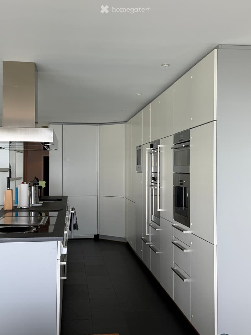 Modern kitchen with white cabinets, stainless steel appliances, and black countertops.