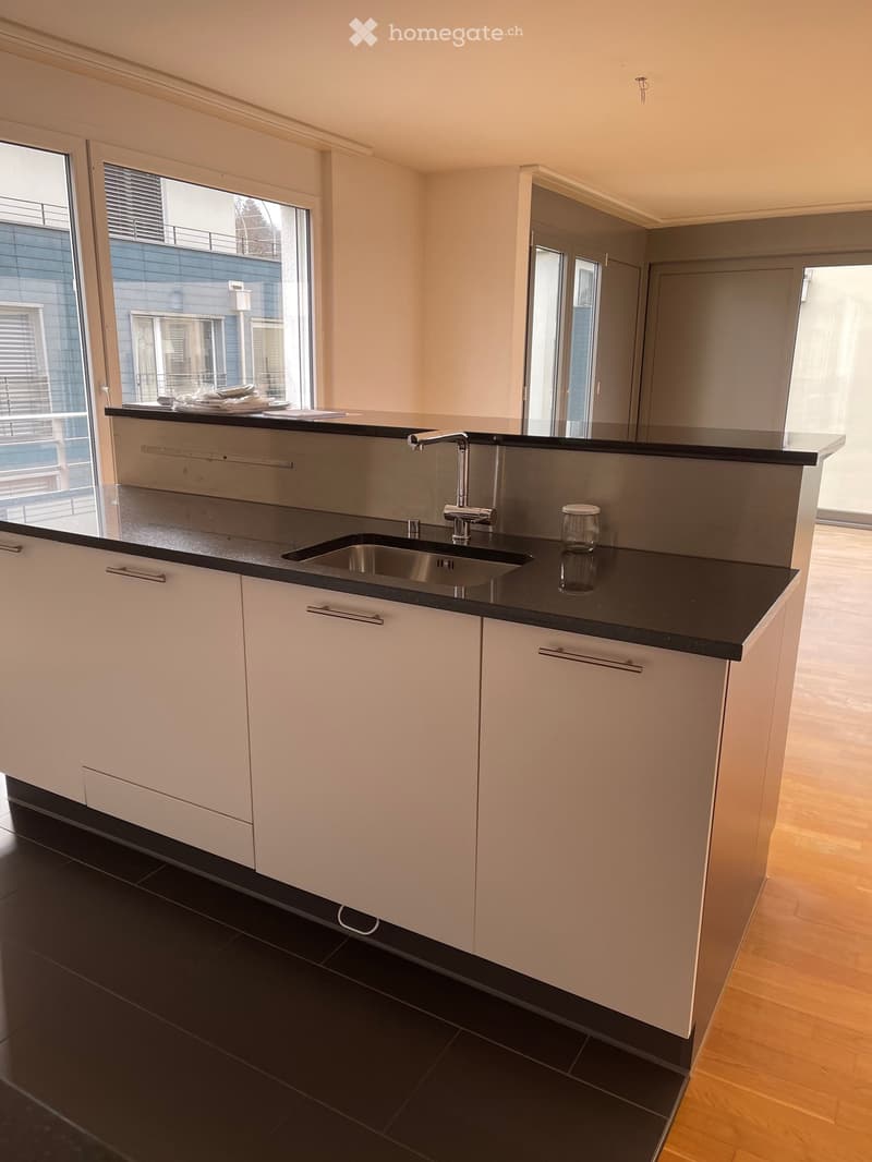modern kitchen with wooden floor, black countertop, stainless steel sink, white cabinets, windows with views of the city