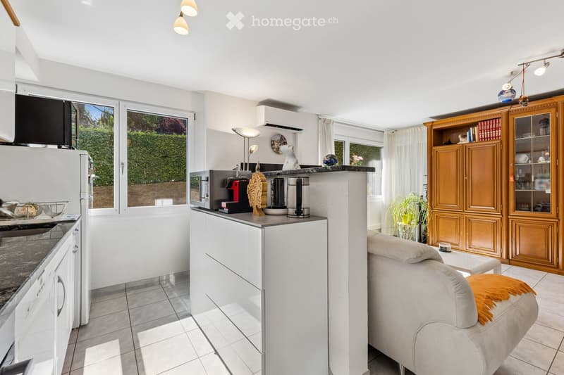 Bright, modern kitchen and living area with white cabinets, a central island, a sofa, and various appliances.