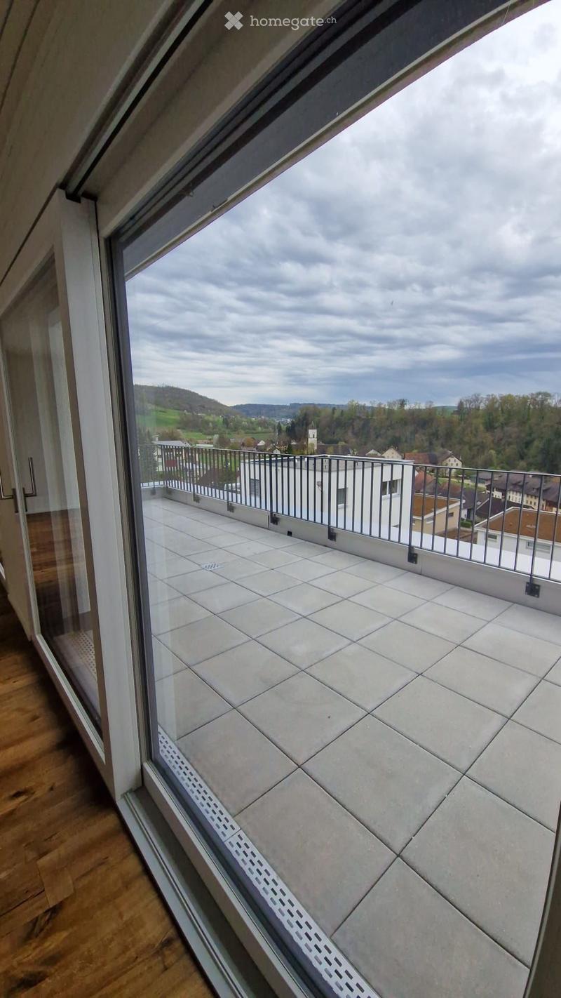 Balcony with tiled floor, metal railing, and scenic view of countryside and town.