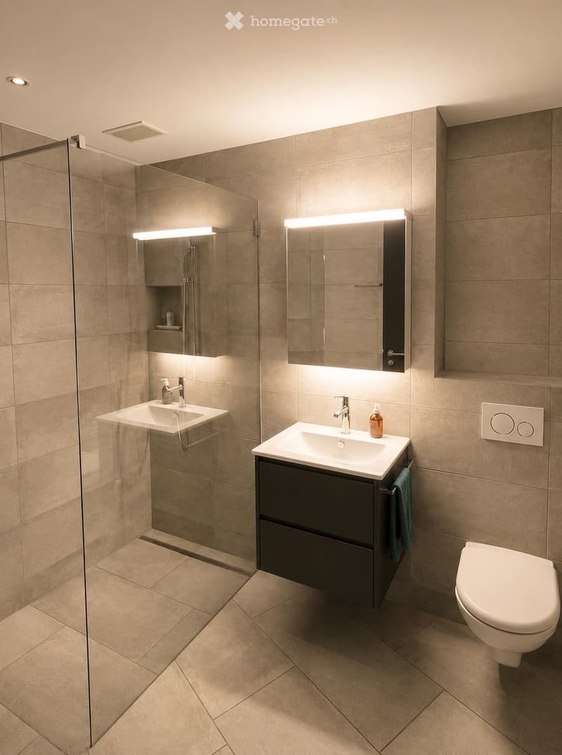 Modern bathroom with two sinks, a toilet, a glass-enclosed shower, and built-in cabinets with mirrors and lighting.