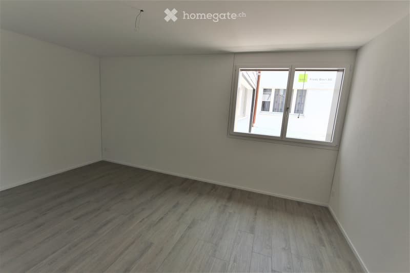 Empty room with wooden flooring and a single window, no furniture or equipment present.