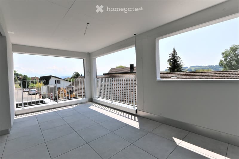 Modern balcony with tiled floor, white walls, large windows offering scenic views, and metal railings.