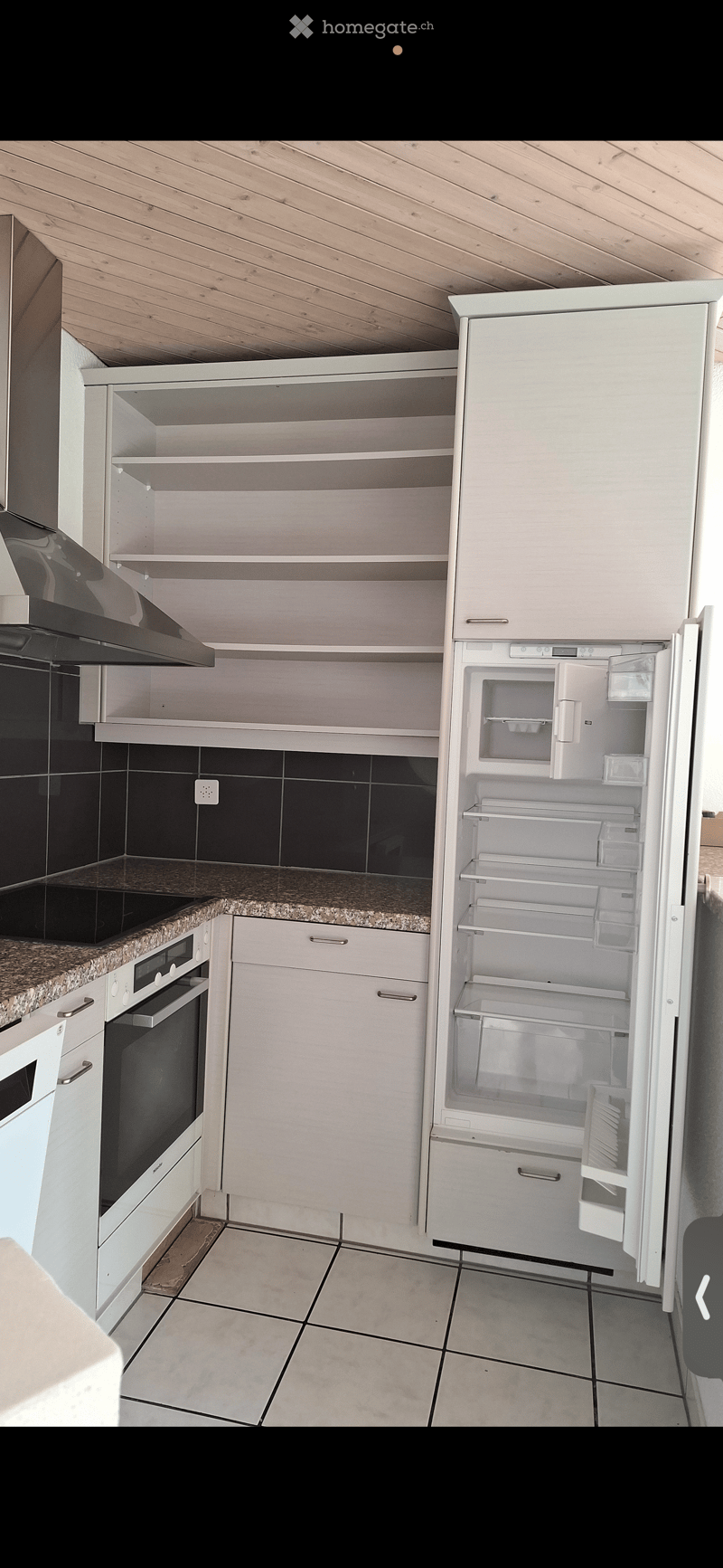 Modern kitchen with white cabinets, granite countertop, and stainless steel appliances including an open refrigerator and oven.