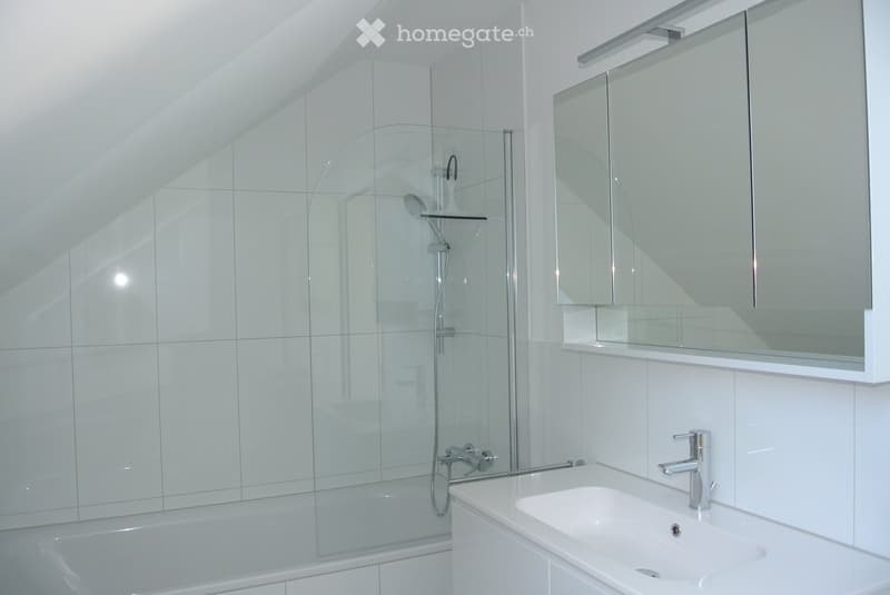 Modern bathroom with white tiles, a bathtub, a glass-enclosed shower, a sink with a modern faucet, and a mirrored cabinet above the sink.