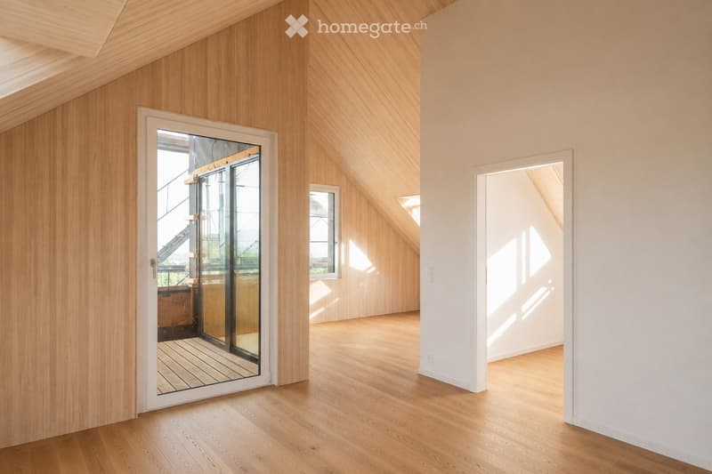 Bright, empty room with wooden walls and floor, large windows, and sliding glass doors leading to an outdoor area.