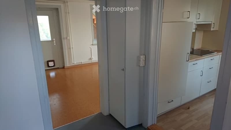 Empty room with light wooden flooring, white walls, and a doorway leading to another room. No furniture or equipment is present.