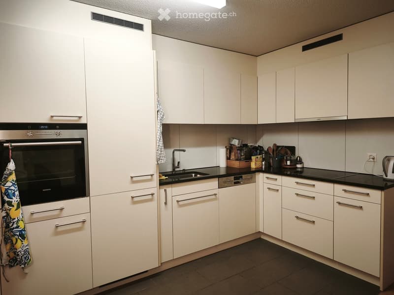 Modern kitchen with white cabinets, stainless steel appliances, and a black countertop.