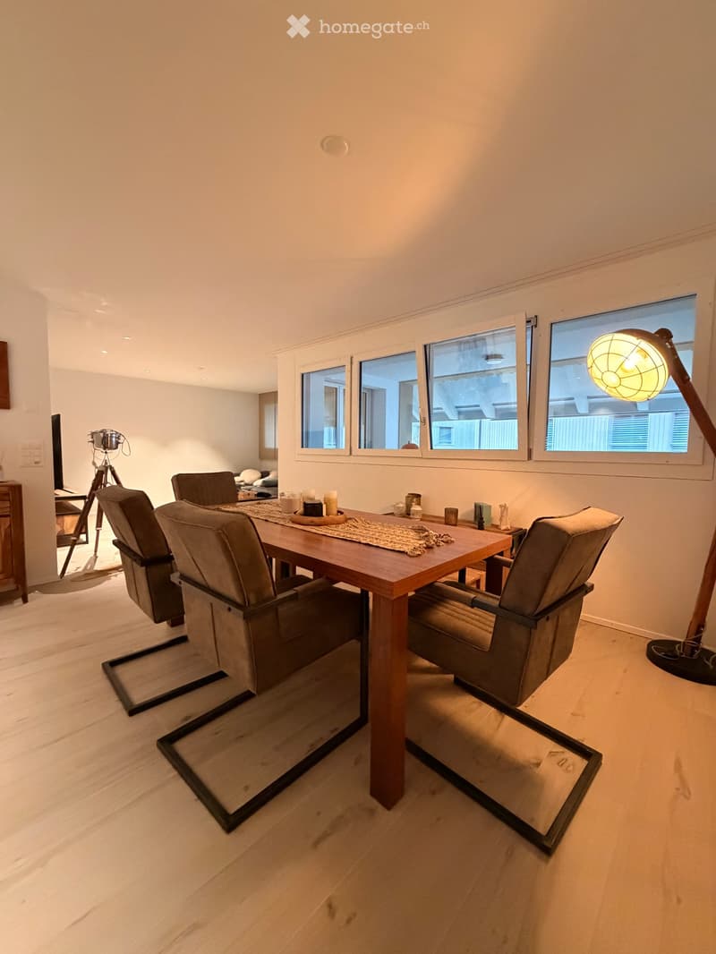 Dining area with a wooden table, four chairs, and a floor lamp near the window.
