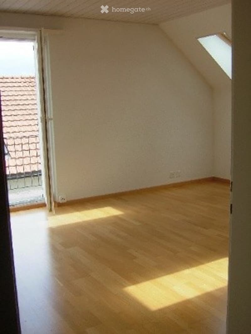 Empty room with wooden flooring, white walls, and a large window opening to a balcony. No furniture or equipment present.