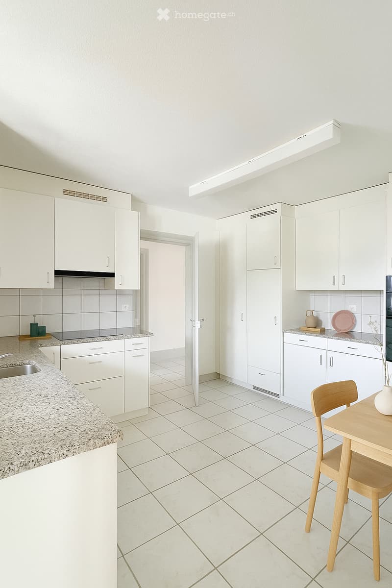 Modern kitchen with white cabinets, granite countertops, tiled floor, and a small dining area with a table and chairs.