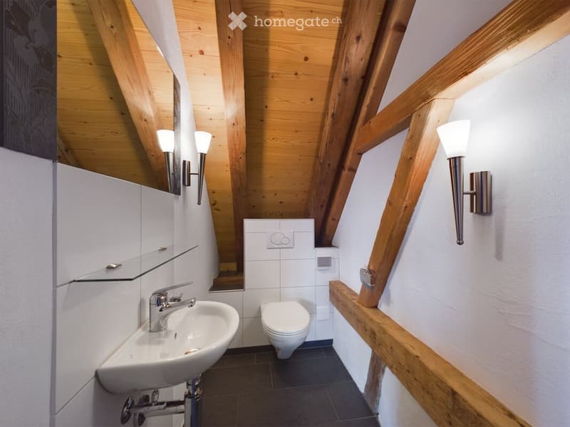Bathroom with sink, toilet, wooden exposed ceiling, wall-mounted lamps