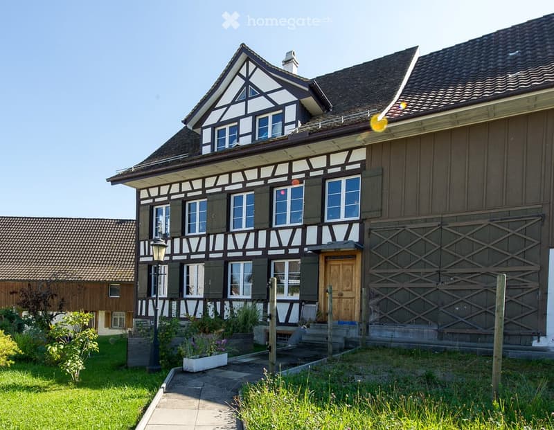 two story house, brown and white paint, gable roof, multiple windows, small garden