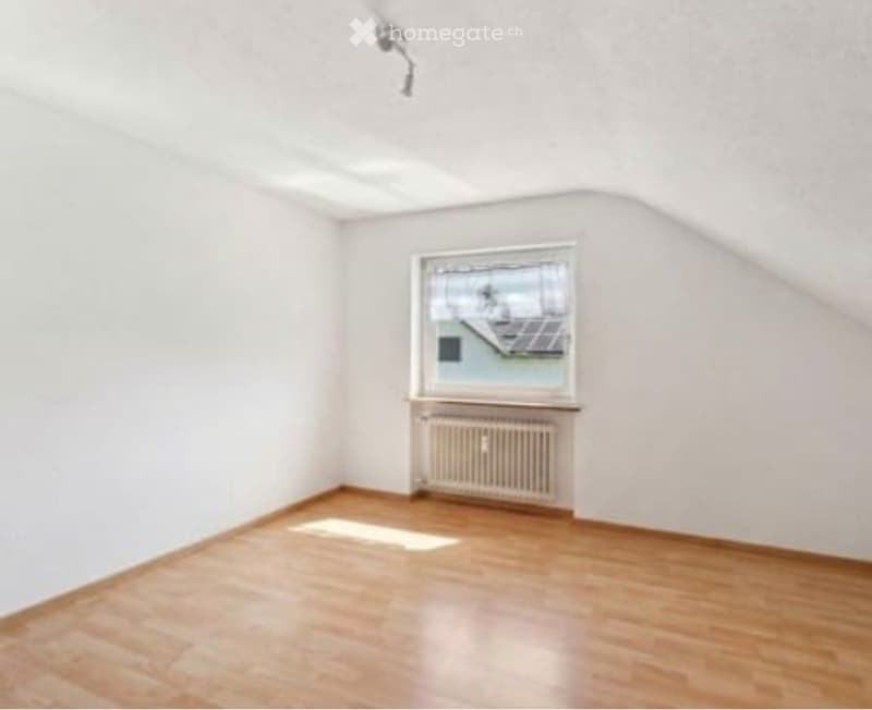 Empty room with wooden flooring, white walls, a single window, and a radiator below it.