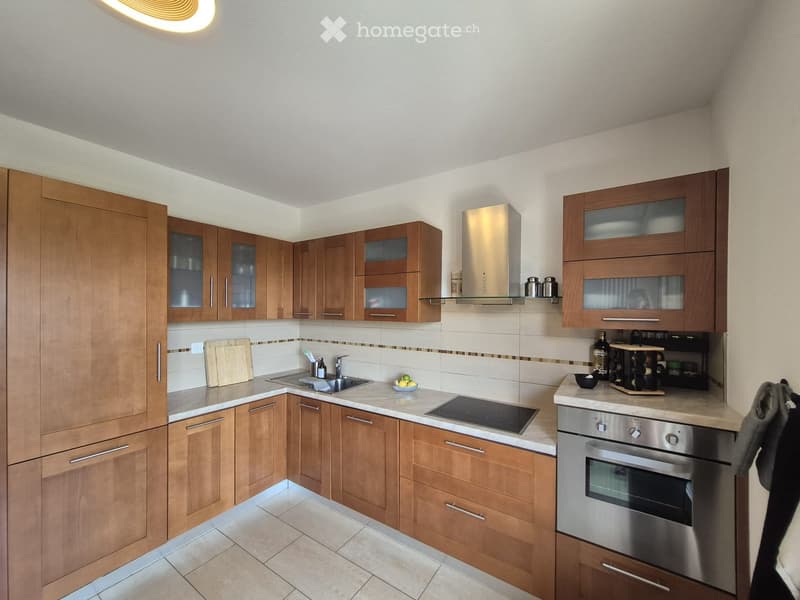 Modern kitchen with wooden cabinets, stainless steel appliances, and a marble countertop.