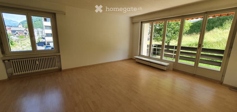 Empty room with wooden flooring, large windows, and radiators. No furniture or equipment present.