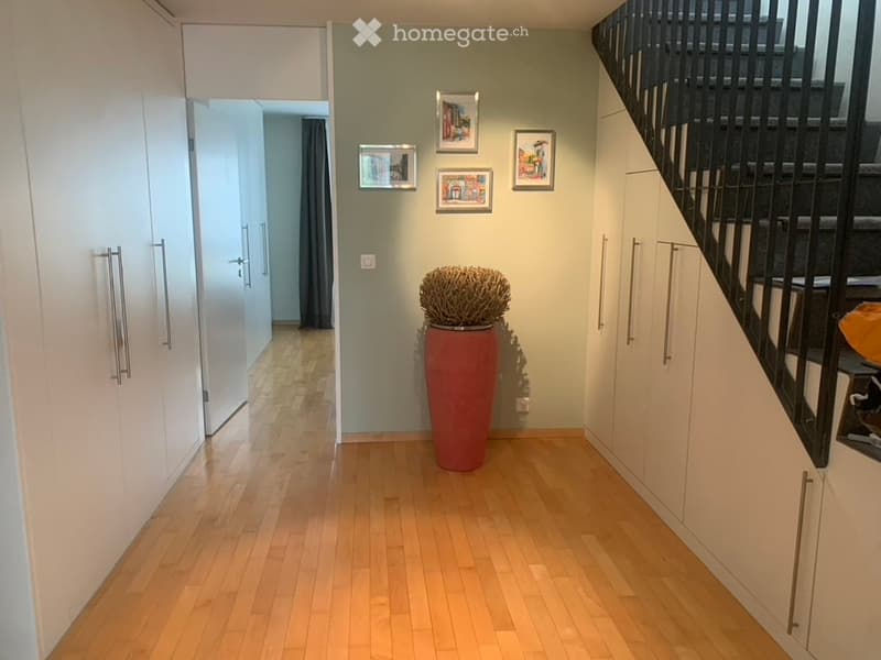 Hardwood floors, white cabinets, stairs, picture frames on the wall, a large plant in a red pot