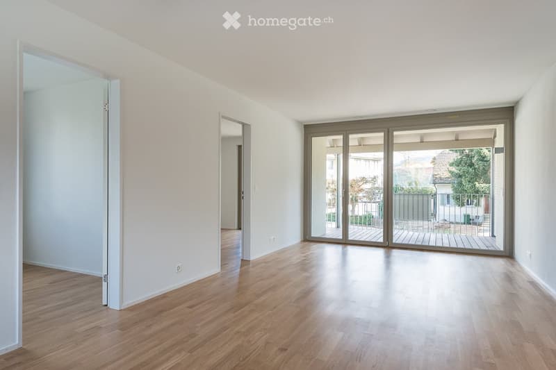 Empty room with wooden flooring, large sliding glass doors leading to a balcony or terrace, and neutral-colored walls.