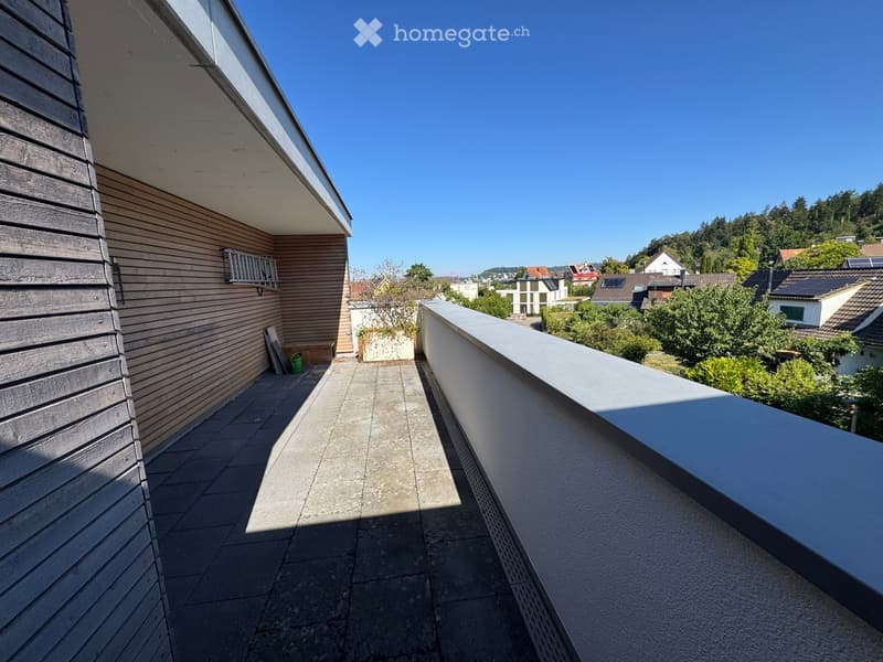 Balcony with wooden siding, tiled floor, and a view of a suburban neighborhood with houses and greenery.