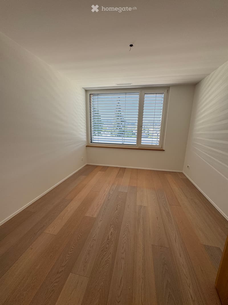 Empty room with wooden flooring, white walls, and a window with blinds. No furniture or equipment present.