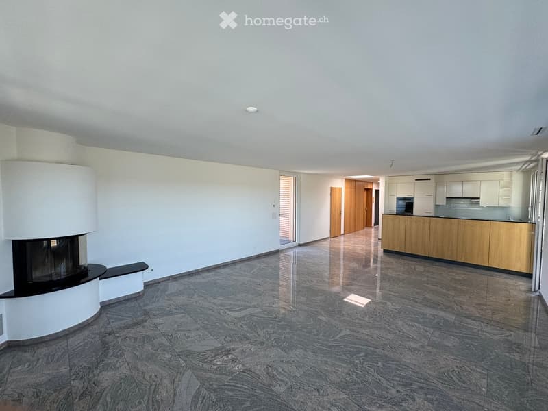Open-plan living and kitchen area with polished marble floors, a modern fireplace, and light wooden kitchen cabinets.