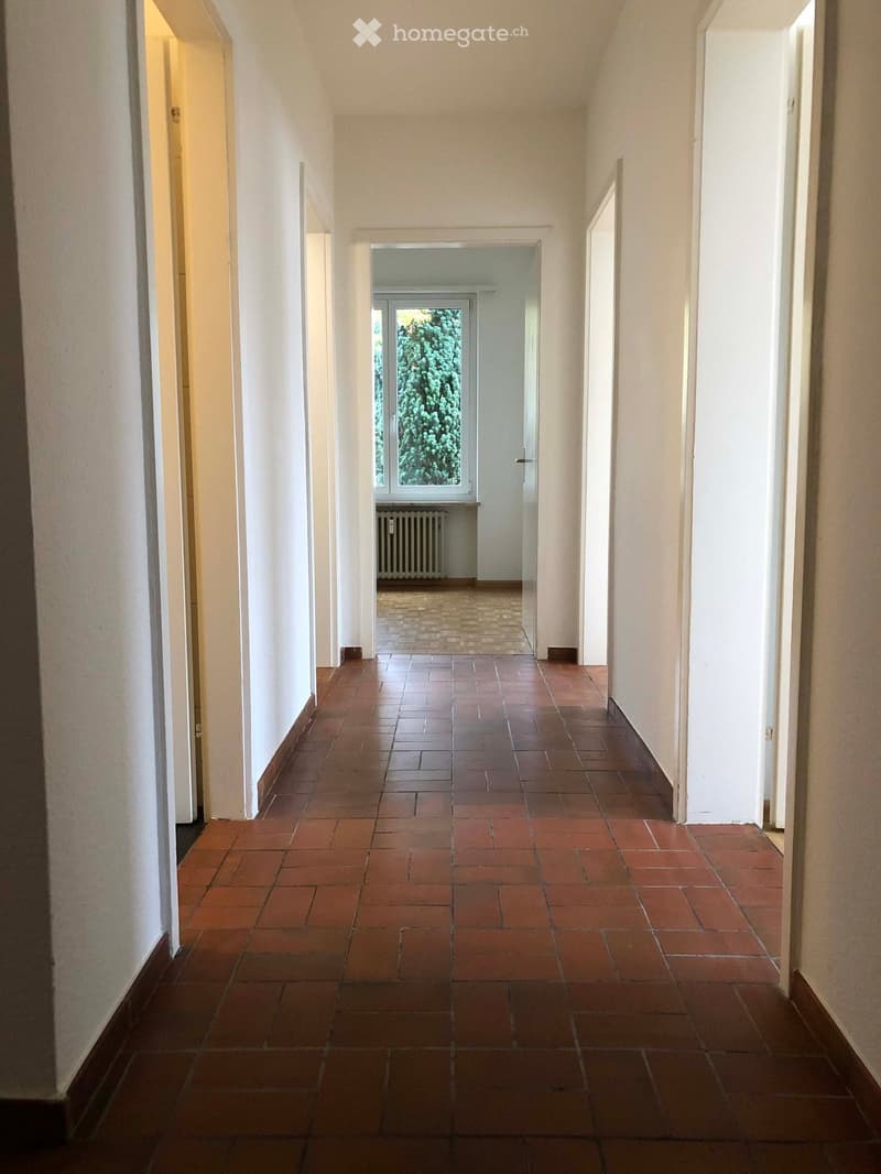 Empty hallway with red brick flooring and white walls