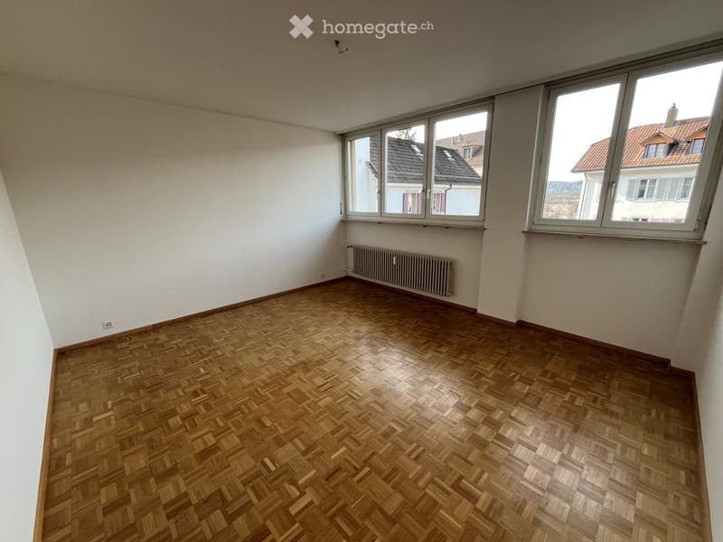 Empty room, wooden floor, two large windows, white walls, wall-mounted radiator