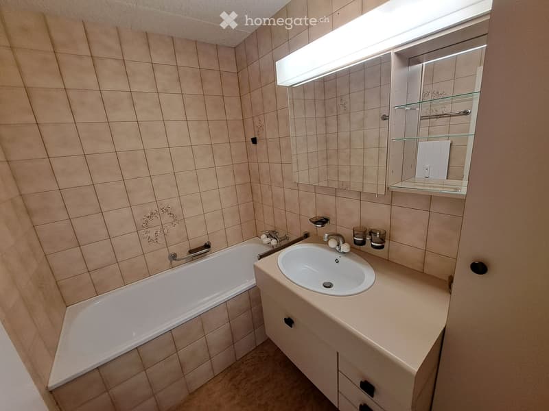 Bathroom with a bathtub, sink, mirror, and two cups on the counter.