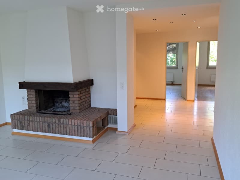 Empty hallway with tiled floor, white walls, recessed lighting, and a brick fireplace on one side.