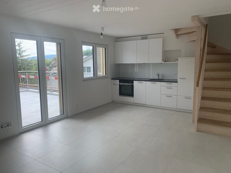 Modern kitchen with white cabinets, a sink, and an oven. Large windows and a sliding glass door lead to a balcony.