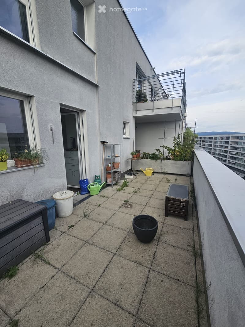 Balcony with concrete floor, small wooden bench, potted plants, and gardening tools.