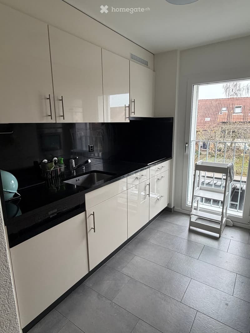 kitchen, black countertop, white cabinets, stainless steel sink, white floor, dishwasher, washing machine, balcony