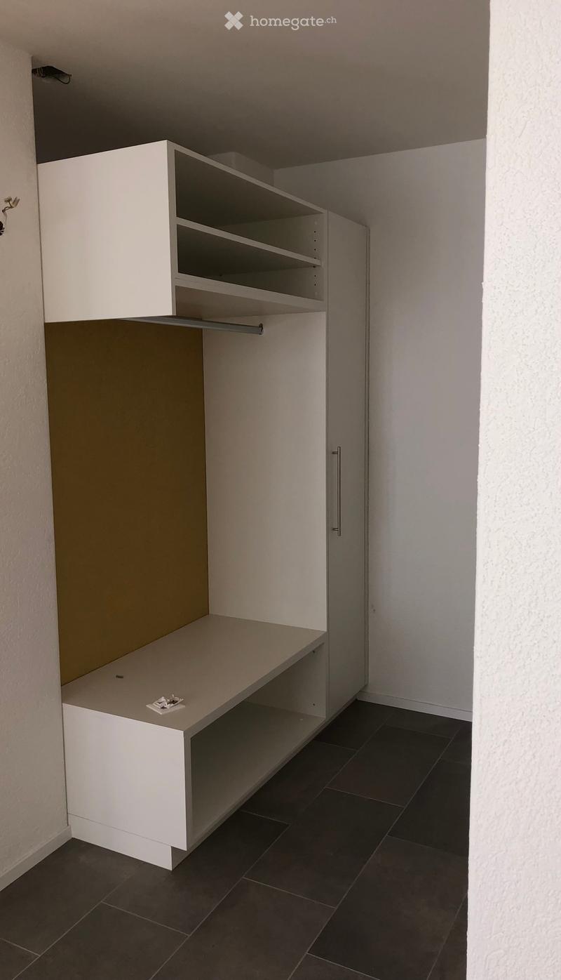 white shelf, closet with door, white desk with open shelves, beige wall, gray tile flooring