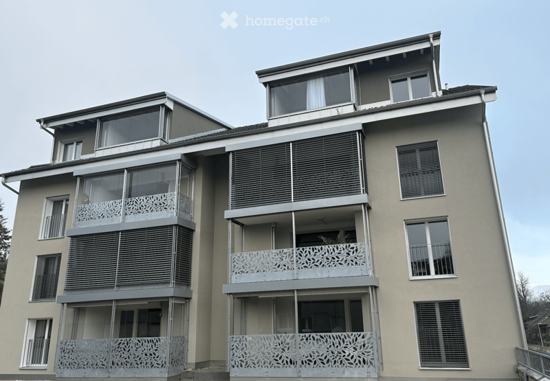 Modern 4 story apartment building, large balconies, glass windows, grey walls, grey roof