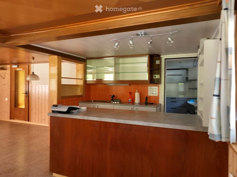 Modern kitchen with wooden cabinets, glass-fronted upper cabinets, stainless steel appliances, and a central island with a countertop.