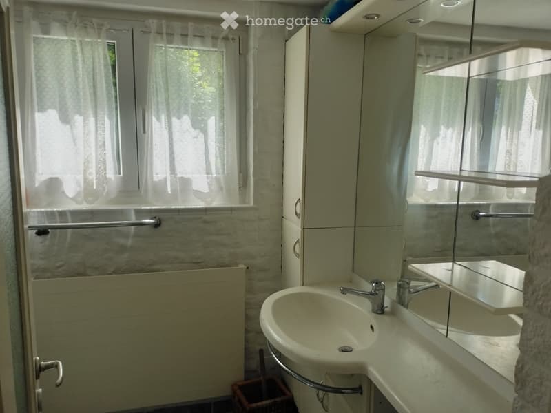 Bathroom with a double sink, mirror, cabinet, and window with curtains.